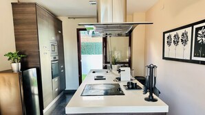 Una cocina moderna con armarios de madera oscura, electrodomésticos de acero inoxidable, una isla central y un ventanal grande.
