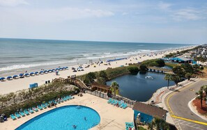 A beach resort with a swimming pool, a small lake, and a boardwalk.