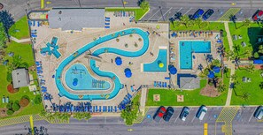 Vista aérea de um complexo de piscinas com várias piscinas, espreguiçadeiras e estacionamento.