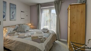 A bedroom with a large bed, a wooden wardrobe, and a window with curtains. - The Old Post Office, Exford (Exford)
