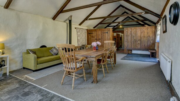 Une pièce chaleureuse avec une table à manger en bois, des chaises, un canapé et un radiateur.