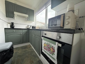 Una cocina con estufa, horno y ventana.