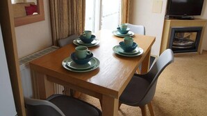 A compact living space with a dining table set for four, a television, and a kitchenette.