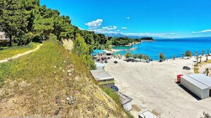 Une zone côtière comprenant un parking, un petit bâtiment et une vue sur la mer et les montagnes.