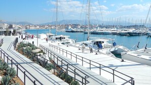 Un port de plaisance avec des bateaux amarrés, une promenade et une vue sur la ville en arrière-plan.