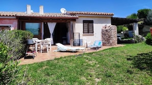 A house with a patio area, outdoor furniture, and a stone wall. - Detached Villa in the most quiet and reserved area (Santa Teresa di Gallura)