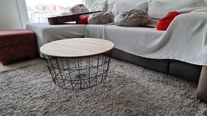 A living room with a round coffee table, a red ottoman, a grey sofa, and a guitar. - Beautiful 2-Bed Apartment in Estepona Port (Estepona)