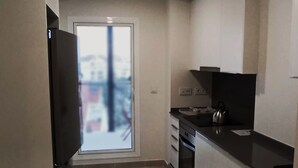 A small kitchen with a black countertop, white cabinets, and a sliding glass door leading to a balcony. - Beautiful 2-Bed Apartment in Estepona Port (Estepona)