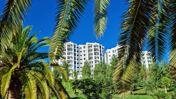 A modern multi-story hotel with a central courtyard, surrounded by lush greenery and palm trees. - Beautiful 2-Bed Apartment in Estepona Port (Estepona)