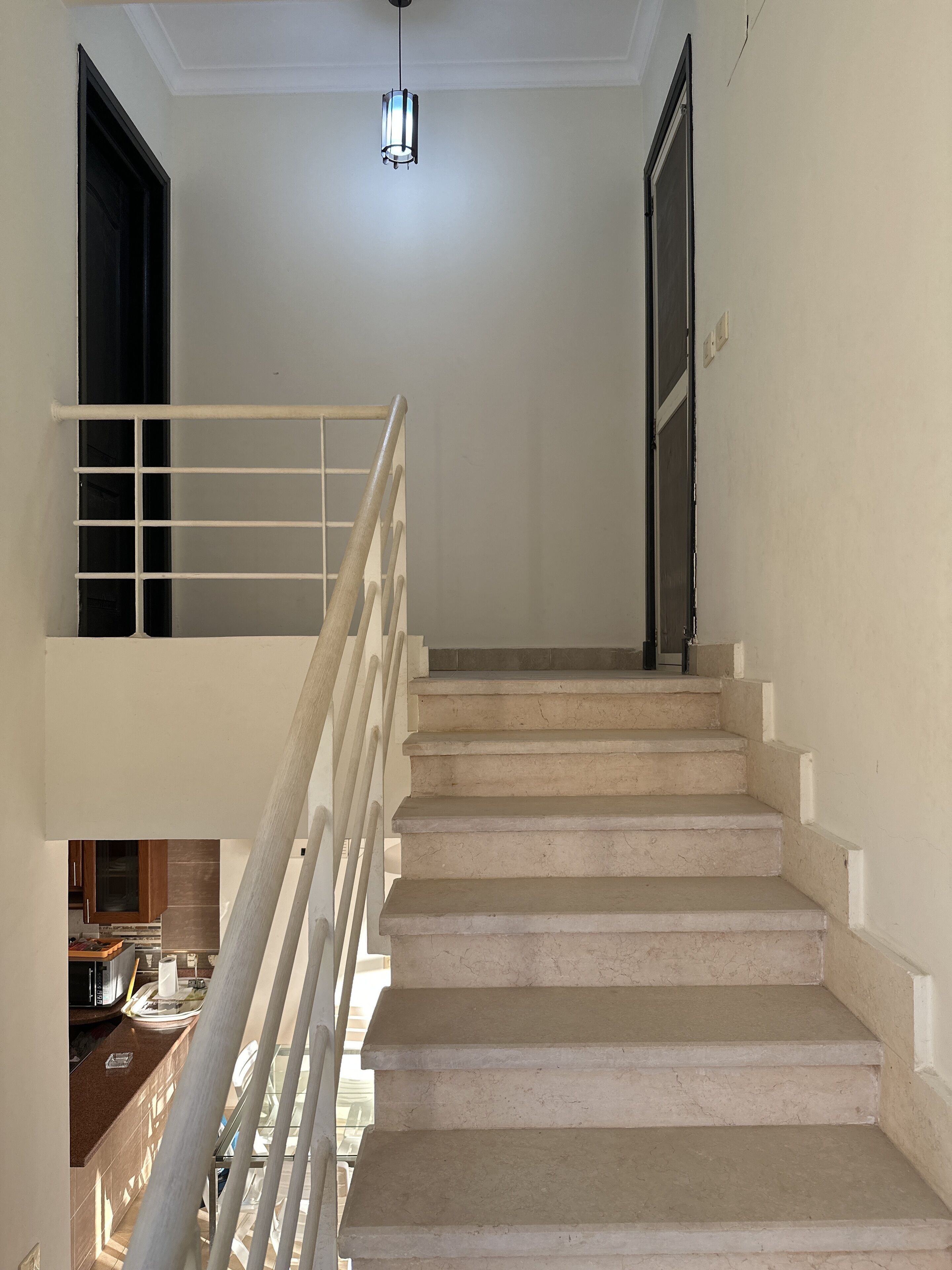 Un escalier avec une rampe blanche menant à un palier.