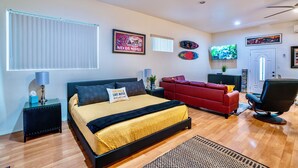 Un dormitorio con cama, sofá rojo, televisor y ventilador de techo.