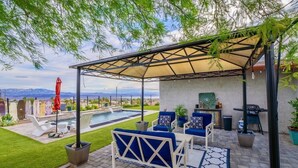 Un patio techado con piscina, mobiliario exterior y vistas a montañas.