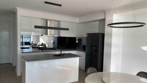 A modern kitchen with a central island, stainless steel appliances, and a dining area with a round table and chairs.