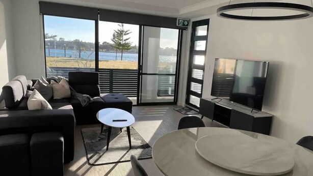 A modern living room with a sofa, a round table, and a TV.
