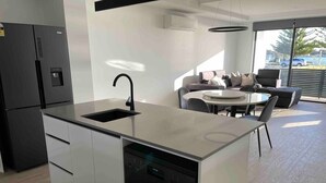 A modern kitchen with a dishwasher, a sink, and a dining area with a round table and chairs.