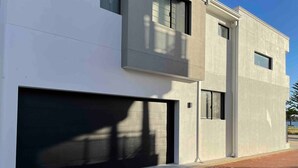A modern two-story building with a large garage door, a flat roof, and a clean, minimalist design.