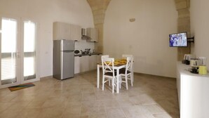 Una cocina amplia con comedor, un televisor montado en la pared y un techo abovedado de piedra.