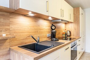 A modern kitchen with a wooden backsplash, stainless steel appliances, and white cabinetry.