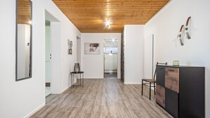 A hallway with wooden flooring, a black cabinet, and a mirror on the left wall.