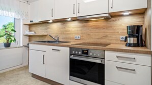 A modern kitchen with white cabinets, a wooden countertop, a built-in oven, and a coffee maker.
