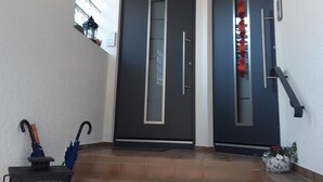 Un ingresso moderno con due porte scure, un piccolo gradino e un lanterna a sinistra.