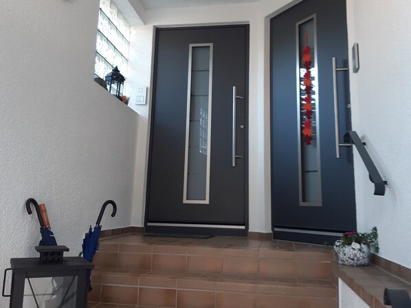 A modern entrance with two dark doors, a small step leading up, and a lantern on the left.