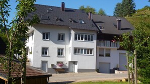 Un edificio residenziale a due piani con tetto in tegole, diverse finestre e un portico anteriore.
