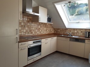 A kitchen with a built-in oven, microwave, and a skylight.