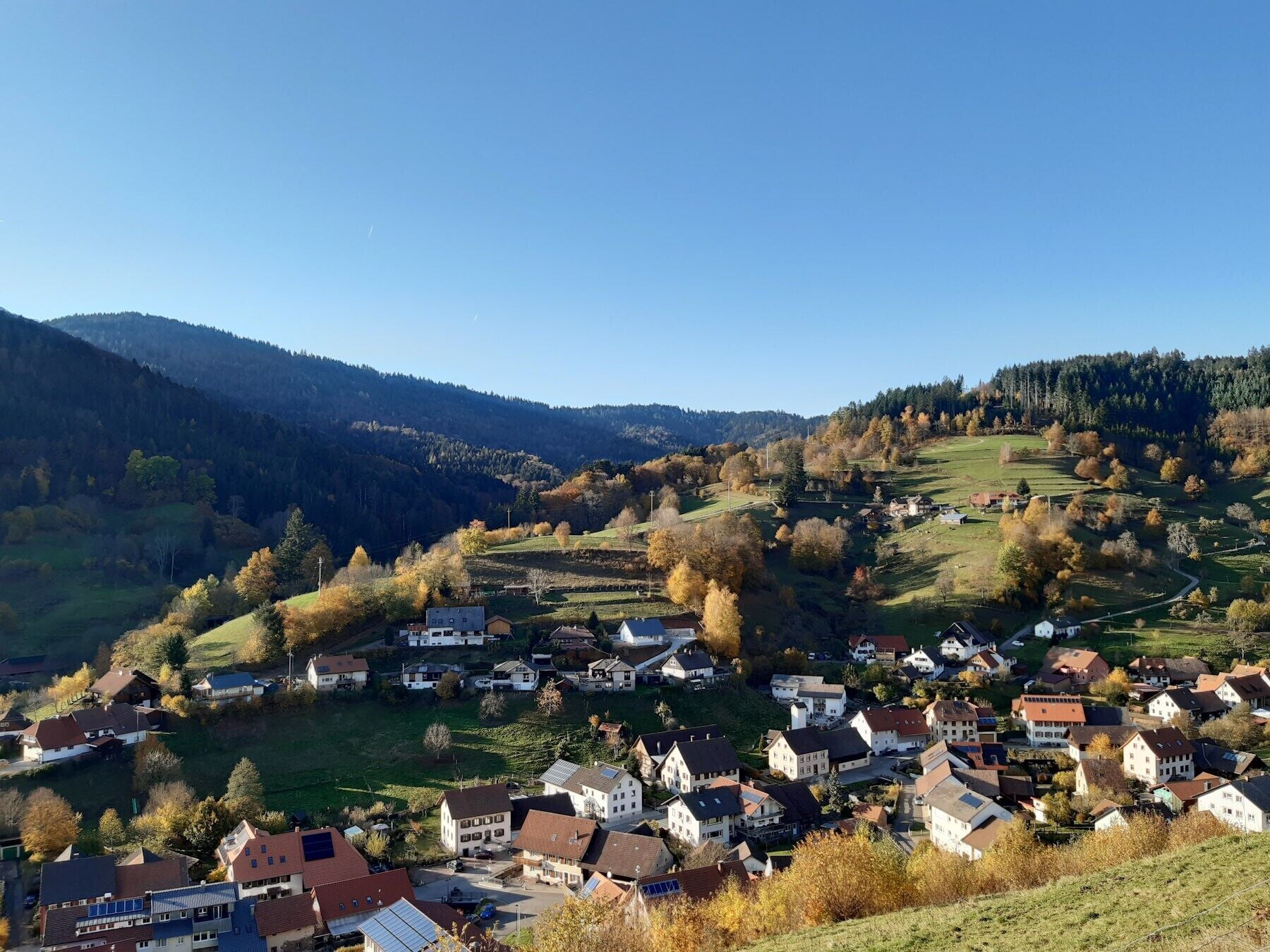 A village with houses, a valley, and mountains in the background.