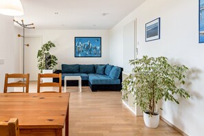 Un salon moderne avec une table à manger en bois, un canapé bleu et des plantes en pot.
