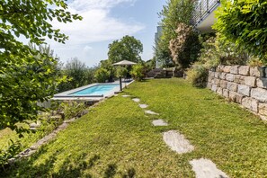 Ein Garten mit Schwimmbad, Steinstufen und einer Steinmauer.
