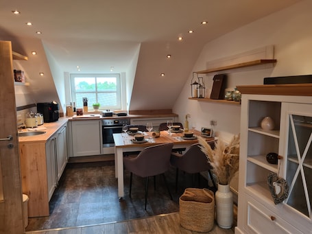 A modern kitchen with a dining area, wooden cabinetry, and a window providing natural light.. Apartment 'Rosenzauber Gipfelstürmer' with Shared Garden and Wi-Fi