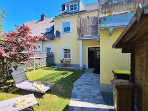 A residential property with a paved patio, a wooden deck, and a small garden area. - Apartment 'Rosenzauber Gipfelstürmer' with Shared Garden and Wi-Fi (Weißenstadt)