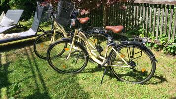 Una bicicleta estacionada sobre césped, con una cerca de madera y una silla al fondo.