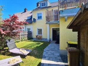 Uma casa com quintal calçado, cerca de madeira e antena parabólica.