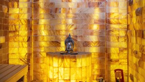 Una habitación con pared de azulejos, una estatua de Buda y una pequeña mesa con una silla.