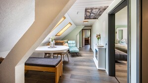 Un dormitorio tipo loft moderno con techo inclinado, un comedor con mesa redonda y una acogedora zona de estar.