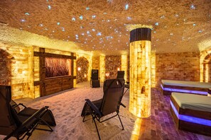A room with a stone wall, a wooden bench, a massage chair, and a bed. - Holiday Apartment 'Salty Sol' with Shared Terrace and Wi-Fi (Leutkirch im Allgäu)