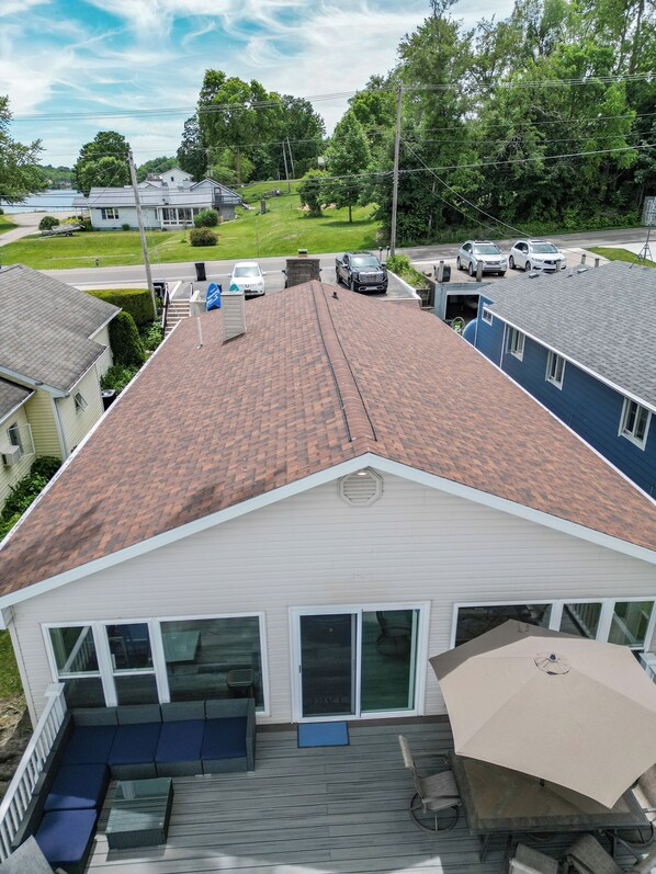 A residential house with a sloped roof, a covered patio with seating, and a garage.