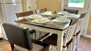 A dining area with a table set for four, surrounded by chairs with leather and wooden frames.