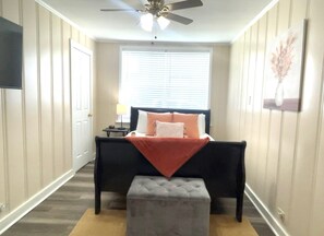 Une chambre à coucher avec un lit, une table de chevet et un ventilateur de plafond.