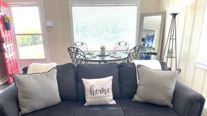 Ein dunkelgraues Sofa mit drei Kissen, davon eines mit dem Aufdruck 'home is our happy place'.