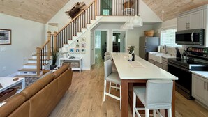 Une cuisine moderne dotée d’un îlot central, d’un coin repas avec un banc et d’un escalier menant à un niveau supérieur.