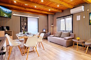 A modern living room with a dining area, wooden flooring, and a large window with curtains. - Pool Estate AquaHaven with Sauna & Jacuzzi, Veliko Trgovišće, Croatia (Veliko Trgovišće)