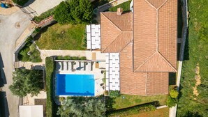 Eine Vogelperspektive eines Anwesens mit Swimmingpool, einer Liegefläche und einem großzügigen, überdachten Patio.