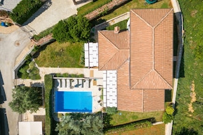 An aerial view of a property with a swimming pool, a patio area, and a large tiled roof structure.