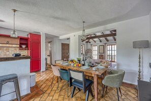 A dining area with a wooden table set for four, surrounded by chairs, a red cabinet, and a hanging light fixture.