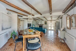 A spacious dining area with a wooden table set for a meal, surrounded by chairs.