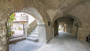 A stone corridor with arches, a staircase, and a gate.