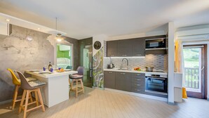 A modern kitchen with a central island, built-in appliances, and a view to the outside.